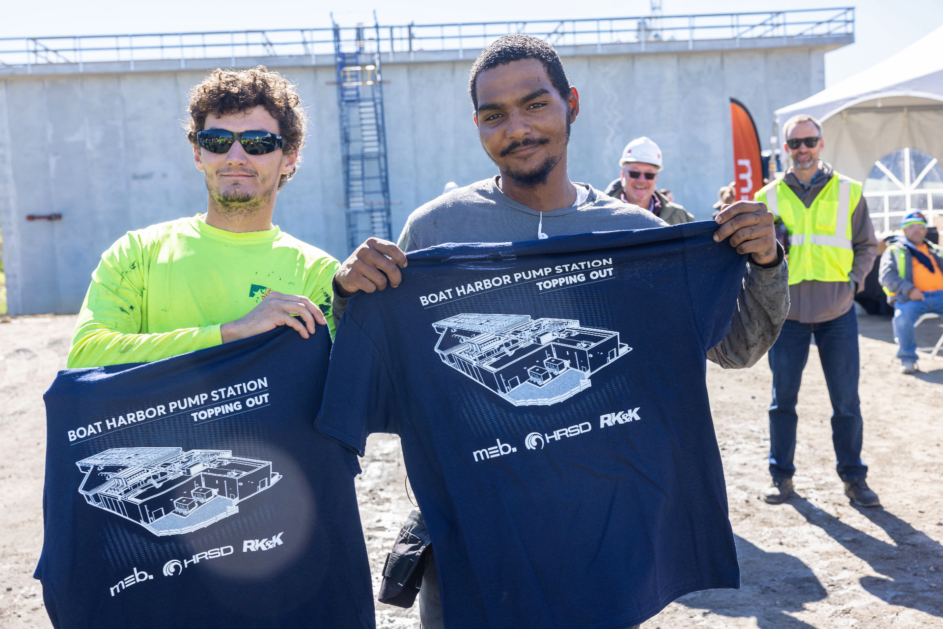Construction crew holding custom Boat Harbor Pump Station topping out shirts by Excel Sportswear